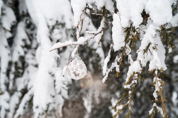Horizontal view of christmas ornament with a reindeer hanging from a pine covered with snow outdoors. Seasonal winter december concept. White snowy background with copyspace festive christmas.