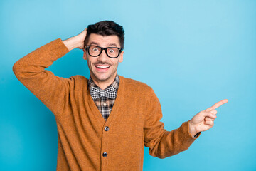 Photo of astonished man point finger empty space hold hand head wear glasses isolated on blue color...