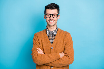 Photo of cheerful funny young man hand wear brown cardigan spectacles arms crossed isolated blue...