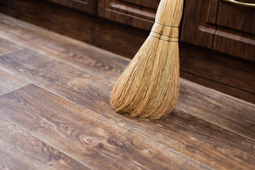 Cleanliness and order at home, a broom of sorghum for sweeping is on the floor against the wall in the kitchen, cleaning equipment, routine household chores