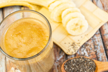 Banana smoothie with chia in a glass on a wooden table. Top view. Selective focus