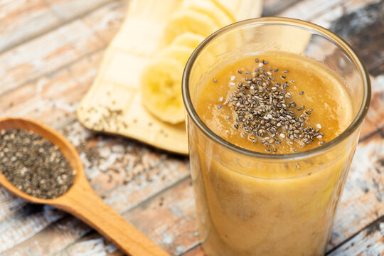 Homemade smoothie with bananas and chia seeds in glass on wooden background. Selective focus
