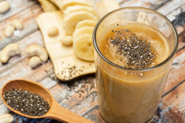 Homemade smoothie with bananas and chia seeds in glass, low angle view. Selective focus