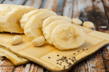 Ripe bananas and a sliced on wooden cutting board, close up. Selective focus.