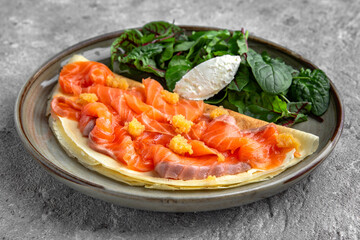 Pancakes with tender fillet of salted salmon with caviar, cheese and herbs. Delicious, hearty, nutritious breakfast. Balanced nutrition for beauty and health.