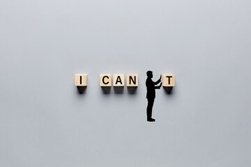 Silhouette of a man changing the word I can't into I can by pushing away the letter. Aspiration, positivity, belief and motivation