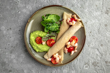 Pancakes with shrimp, cream cheese, guacamole and cherry tomatoes. Delicious, hearty, nutritious breakfast. Balanced nutrition for beauty and health.