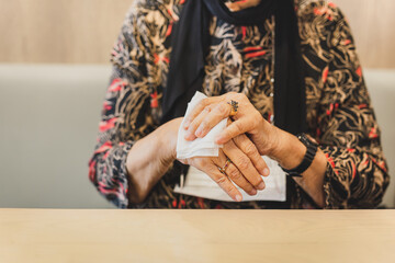 Woman in medical mask cleaning her hands with a wet wipes in restaurant.