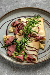 Pancakes with beef slices, Dorblu cheese, herbs and sauce. Delicious, hearty, nutritious breakfast. Balanced nutrition for beauty and health.