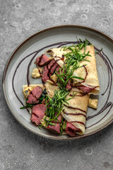 Pancakes with beef slices, Dorblu cheese, herbs and sauce. Delicious, hearty, nutritious breakfast. Balanced nutrition for beauty and health.