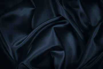 Black blue abstract background. Dark blue silk satin texture. Beautiful wavy soft folds on the surface of the fabric. Navy blue elegant background with copy space for your design. Web banner.