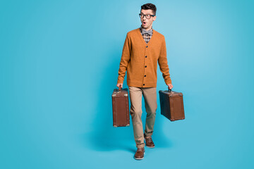Full size photo of young man amazed shocked surprised go walk hold suitcase look empty space isolated over blue color background