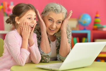 portrait of happy grandmother and daughter using laptop