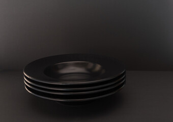A simple composition of a stack of black plates on a black background.