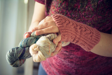 Woman hands with knitted mittens holding artisanal dyed yarn skein - Handcraft cozy warm lifestyle hobby
