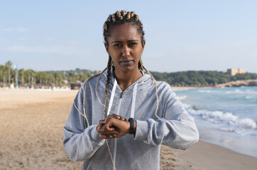 Black woman in sportswear and a watch looking at the camera outdoors