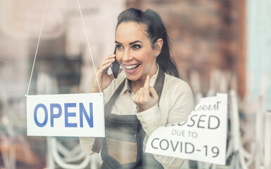 Beautiful waitress excitingly announces news on a phone about restaurant reopening as covid-19...
