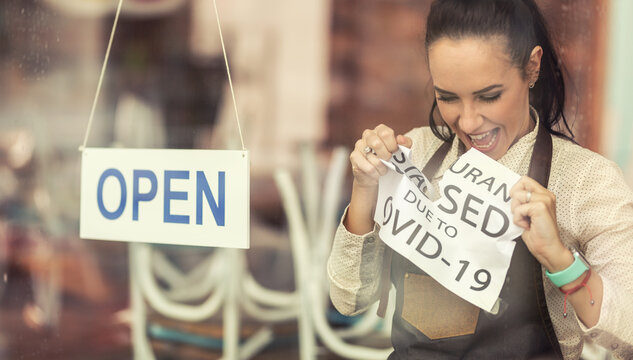 Happy restaurant owner tears apart a sign about closure due to Covid-19 as services reopen after the pandemic