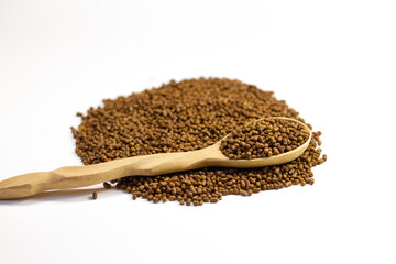 Buckwheat tea in a wooden spoon on a white background. Isolate. Buckwheat tea close-up macro photography. Scattered buckwheat tea pellets on white background.