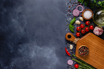 Herbs and condiments on black stone background.