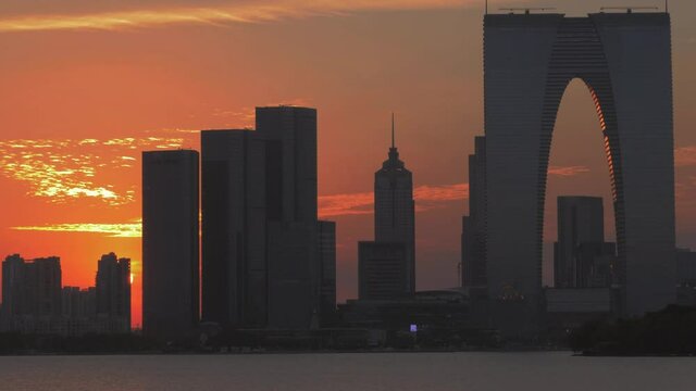 Suzhou, China- March 20, 2019. Colorful sunset behind tall buildings and skyscrapers of downtown with bright sunset lighting. "Gates Of The Orient" modern office buisness building.