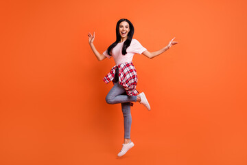 Fototapeta na wymiar Full length profile photo of cheerful nice lady jumping hands sides beaming smile isolated on orange color background