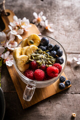 Yogurt with granola and fresh blueberries, in glass bowl over old wood background. Vintage effect.