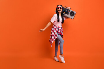 Full length portrait of pretty positive lady carry boombox on shoulder good mood isolated on orange color background