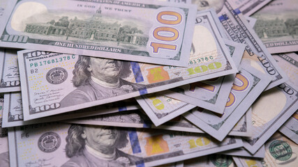 Pile of hundred-dollar US securities is on table. Scattering of bills in close-up. Concept of debt repayment and bribery