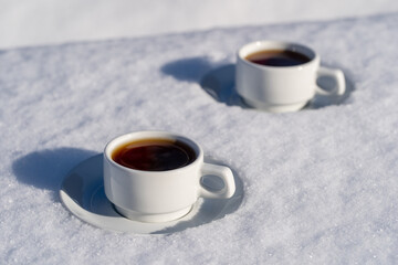 White two cup of hot coffee on a bed of snow and white background, close up