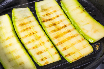 Zucchini cut into plates for making baked rolls are fried in a pan