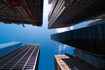 Fototapeta na wymiar Bottom street view on skyscrapers of New York City with blue sky background. Downtown area, wide angle shot, copy space, place for text