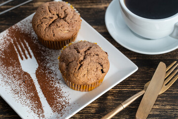 Sweet cherry muffin and white cup with tea on a wooden background
