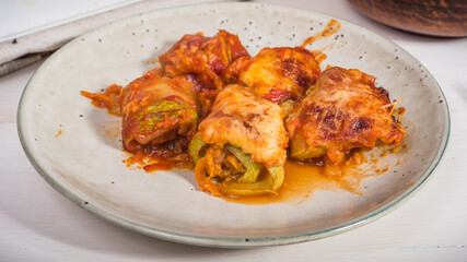 Zucchini rolls with vegetable filling baked with cheese in a plate on the kitchen table