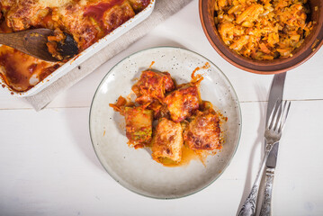 Zucchini rolls with vegetable filling baked with cheese in a plate on the kitchen table