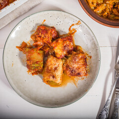 Zucchini rolls with vegetable filling baked with cheese in a plate on the kitchen table