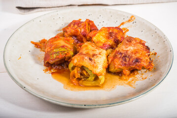 Zucchini rolls with vegetable filling baked with cheese in a plate on the kitchen table