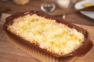 Macaroni with tomato sauce sprinkled with grated cheese in a baking dish ready to bake in the oven - Italian cuisine