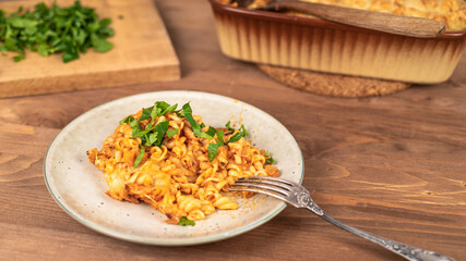 Girandole pasta in tomato sauce baked with cheese on a plate on a wooden table - Italian cuisine