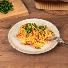 Girandole pasta in tomato sauce baked with cheese on a plate on a wooden table - Italian cuisine