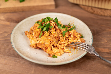 Girandole pasta in tomato sauce baked with cheese on a plate on a wooden table - Italian cuisine