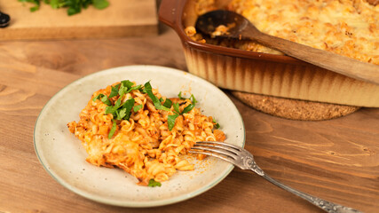 Girandole pasta in tomato sauce baked with cheese on a plate on a wooden table - Italian cuisine