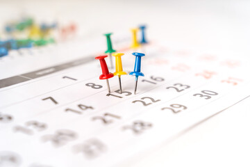 Lots of colorful pins on the calendar close-up with selective focus. The concept of planning.