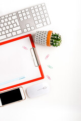 Office background on a white desk with notepad, keyboard and mobile phone. Top view, copy space