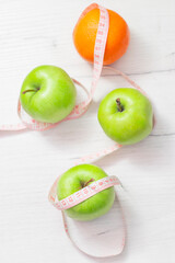 Measuring tape wrapped around two green apple and orange isolated on white background, Concept of the goal to lose weight,the goal of diet,