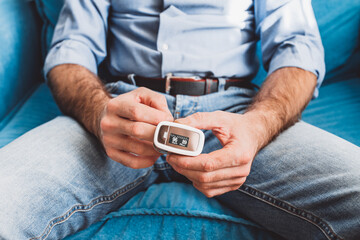 Man monitors heart rate and oxygen levels with a handheld pulse oximeter
