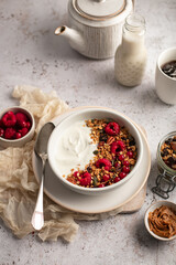 Petit déjeuner avec bol de granola, yaourts et framboises