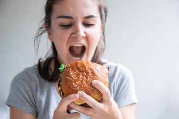 Close up portrait of a hungry young woman eating burger over white background