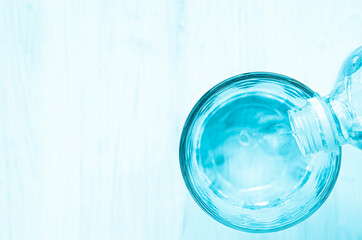 Pouring water from bottle into glass on background