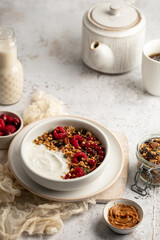 Petit déjeuner avec bol de granola, yaourts et framboises